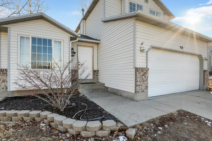 White siding exterior with brick accents, attached two-car garage, concrete driveway, and front entry