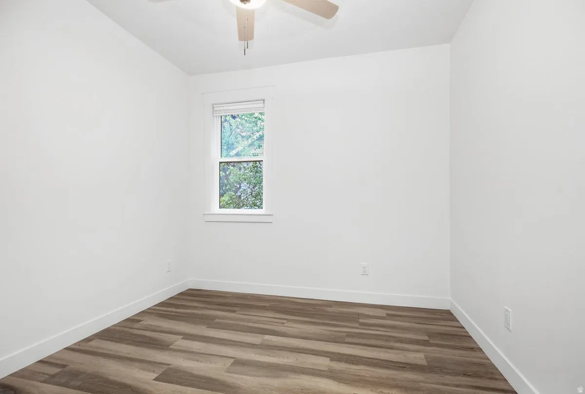 Room featuring a ceiling fan, a window with blinds, and wood-finish flooring