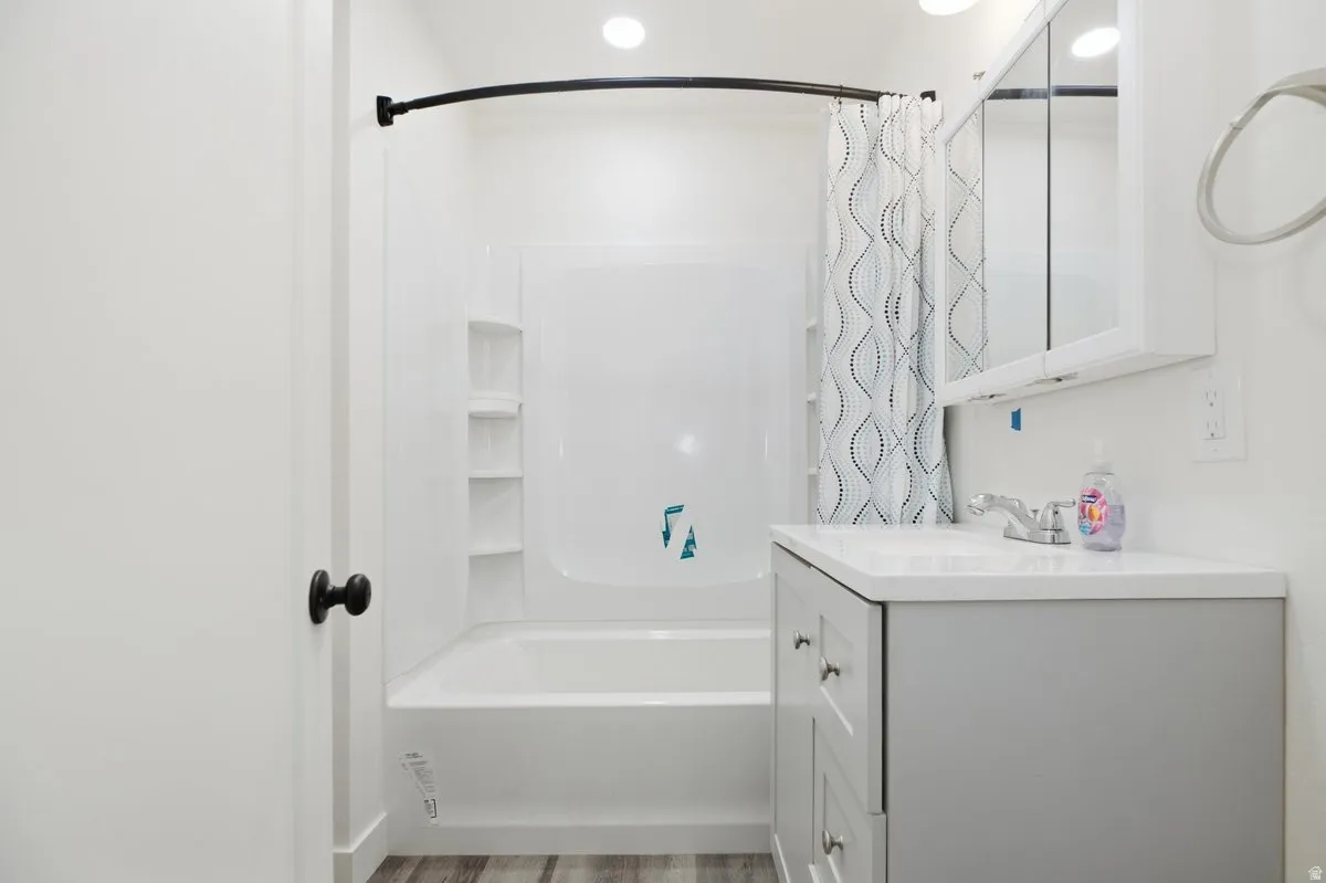 Bathroom featuring a tub/shower combination with built-in shelving, a single vanity with a white countertop, and a medicine cabinet