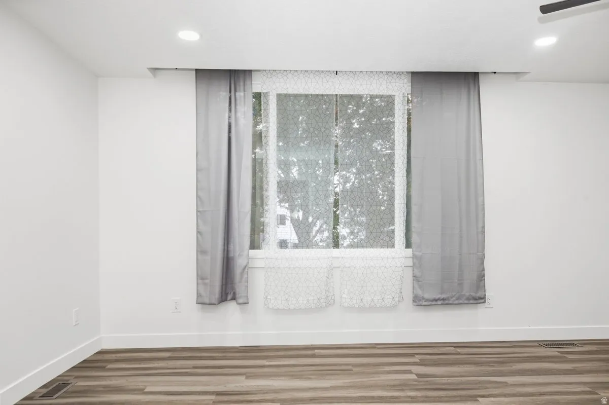 Recessed lighting, wood-finish flooring, white walls, and a large window