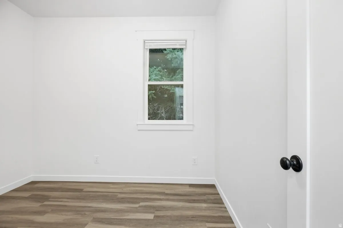 Neutral white wall finish, wood-finish flooring, white window trim, and black door hardware
