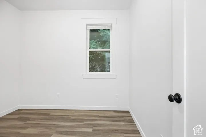 Neutral white wall finish, wood-finish flooring, white window trim, and black door hardware
