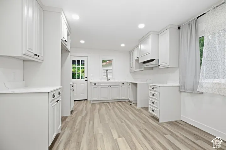 White cabinetry with dark hardware, wood-finish flooring, recessed lighting, and a subway tile backsplash