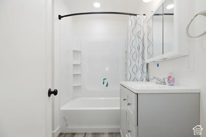 Bathroom featuring a tub/shower combination with built-in shelving, a single vanity with a white countertop, and a medicine cabinet