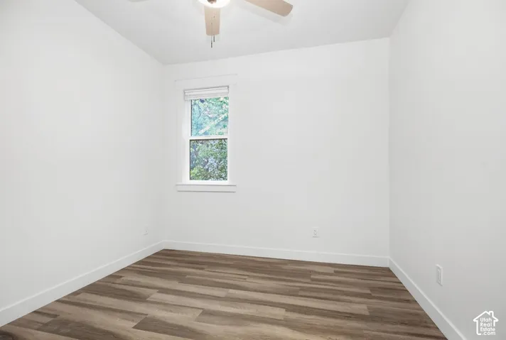 Room featuring a ceiling fan, a window with blinds, and wood-finish flooring
