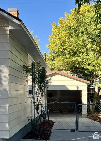 Siding exterior with a brick chimney and a detached single-car garage