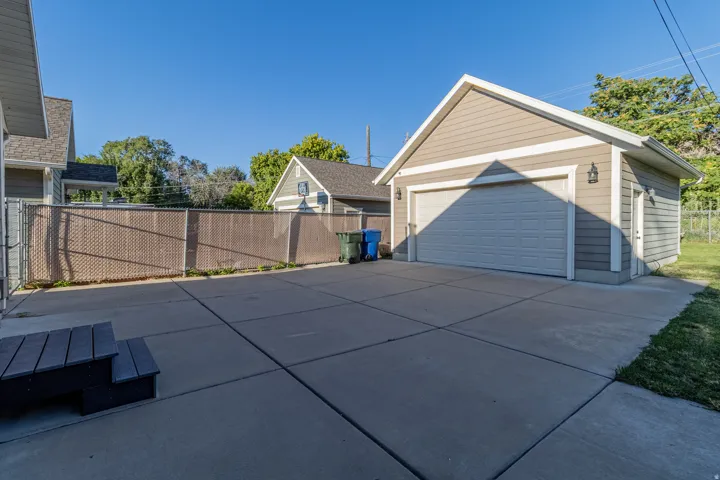 Detached garage with horizontal siding, a paneled garage door, and a side access door