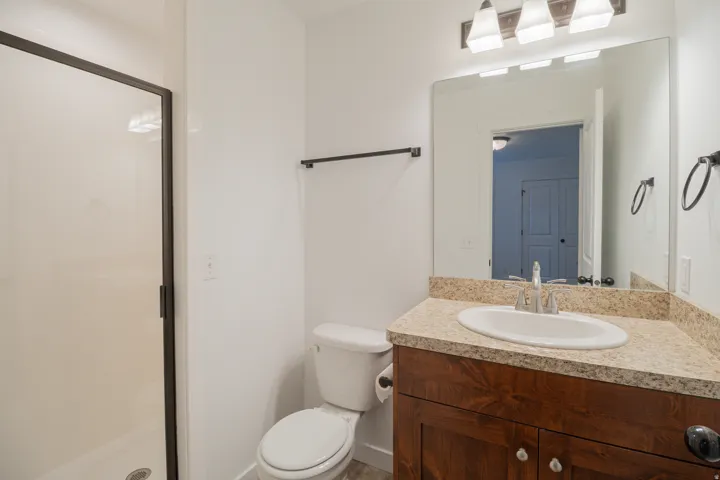 Frameless mirror over a vanity with an undermount sink and granite-finish countertop