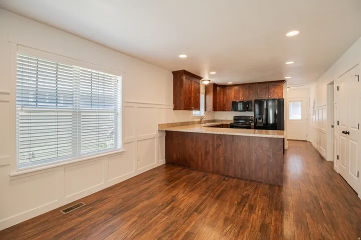 Wood-finish flooring throughout, white wainscoting, recessed lighting, wood cabinetry, and a light-colored countertop