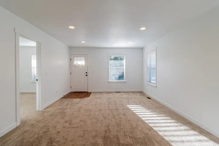 Neutral carpeting throughout, white walls, recessed ceiling lighting, and two windows with blinds