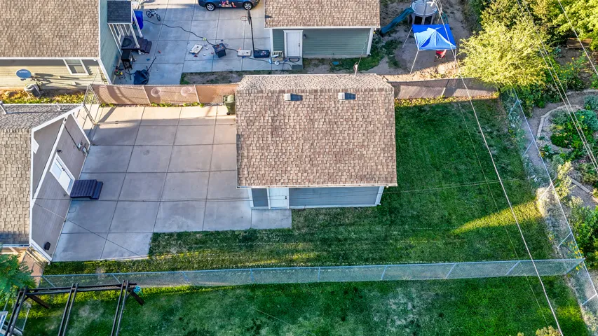 Expansive backyard featuring a manicured lawn, concrete patio, and fenced perimeter