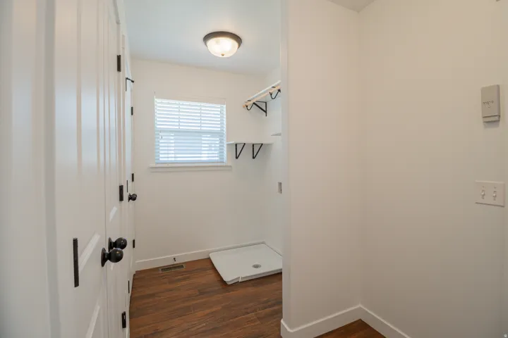 Wood-finish flooring, white walls, and a window with blinds provide natural light