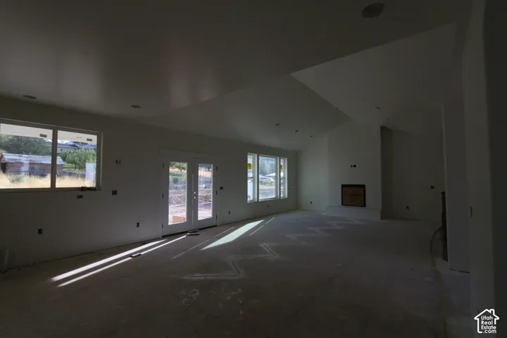 Vaulted ceiling, recessed lighting, double French doors, large windows, and a built-in fireplace