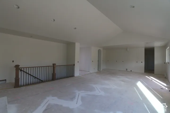 Vaulted ceiling with recessed lighting, integrated wall outlets, and a wood-finish railing with black metal spindles