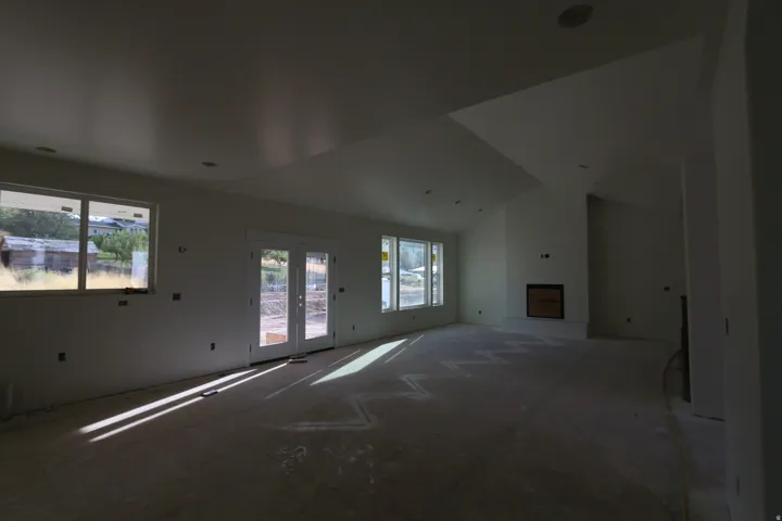 Vaulted ceiling, recessed lighting, double French doors, large windows, and a built-in fireplace