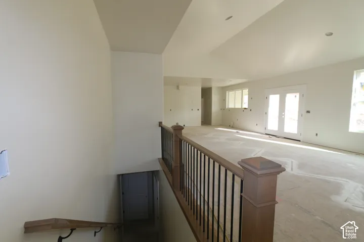 Spacious interior with vaulted ceilings, natural light from multiple windows, and a wood-finish newel post and handrail with black iron balusters