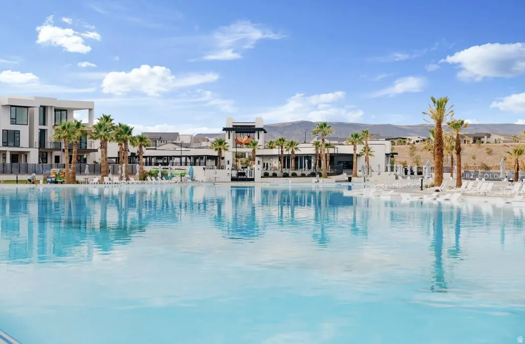 Expansive lagoon with a white sand edge, surrounded by palm trees and modern architectural structures