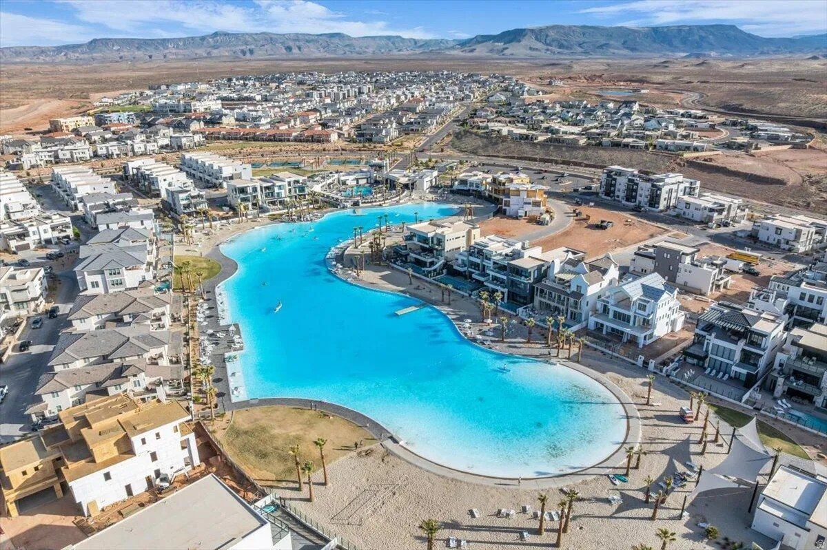Expansive community featuring a large lagoon, residential structures, artificial beaches, and surrounding desert landscape with distant mountains