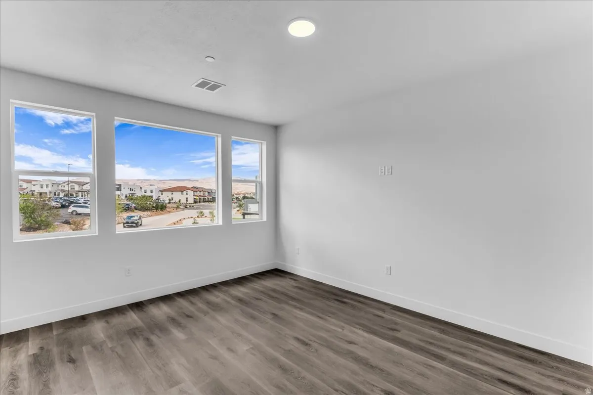 Expansive windows, wood-finish flooring, recessed ceiling lighting, and crisp white walls