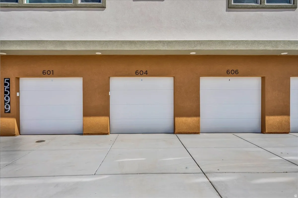 Three individual garage bays with white panel doors and exterior sconces