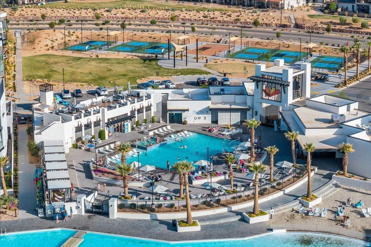 Outdoor recreational area featuring a large swimming pool, multiple tennis courts, and substantial hardscaping