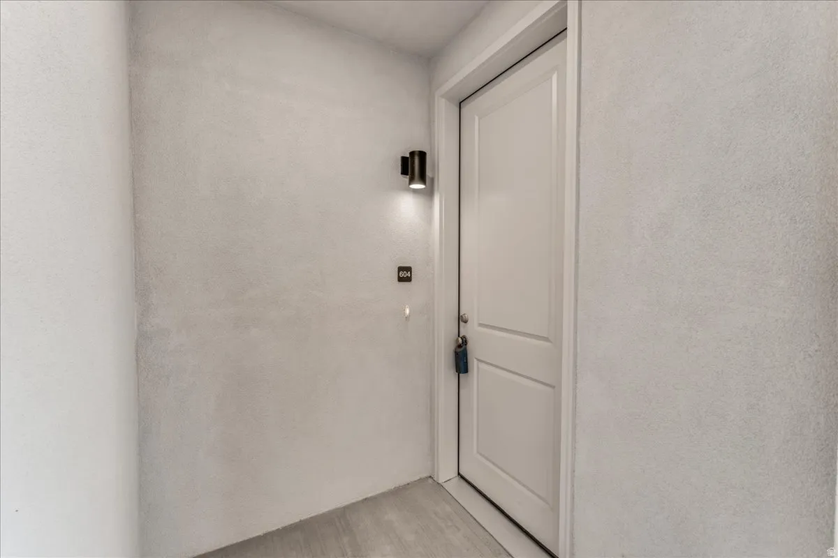 White paneled door with a black wall-mounted light fixture, and textured wall finish