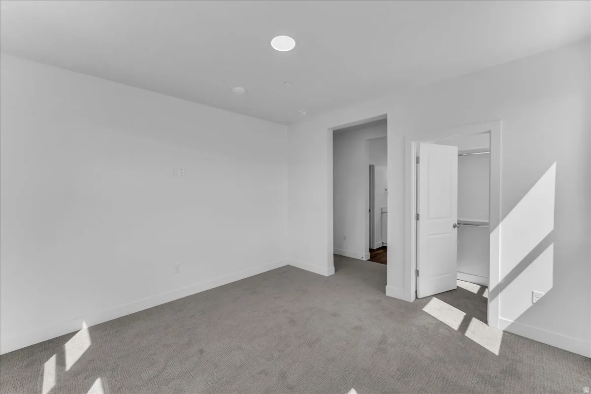 Recessed ceiling lighting, light gray wall-to-wall carpeting, white interior doors, and a built-in closet with shelving