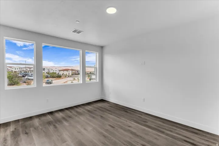 Expansive windows, wood-finish flooring, recessed ceiling lighting, and crisp white walls