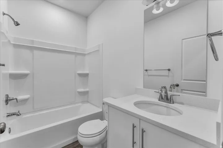 White vanity with a light-toned countertop, oval undermount sink, and chrome faucet