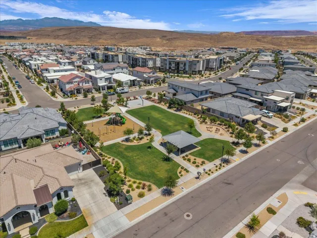 Expansive community park featuring a playground, open lawn areas, and a shaded pergola
