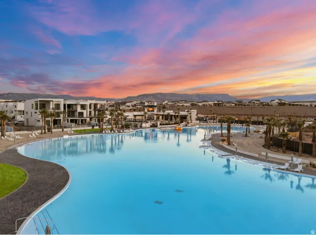 Expansive lagoon with a paved perimeter, surrounded by modern white buildings and palm trees