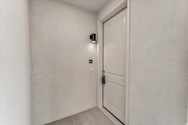 White paneled door with a black wall-mounted light fixture, and textured wall finish