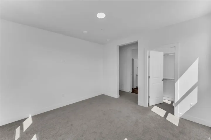 Recessed ceiling lighting, light gray wall-to-wall carpeting, white interior doors, and a built-in closet with shelving