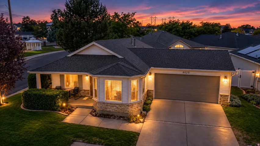 Siding exterior with stone accents, covered entry porch, bay window, attached garage, and paved driveway