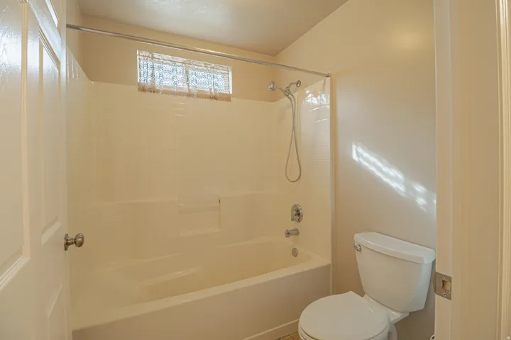 Bathtub with integrated shower, chrome fixtures, and a privacy window