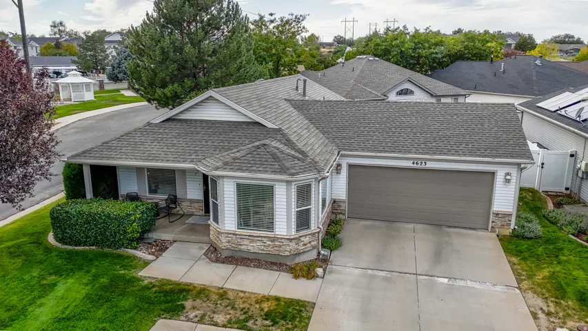 Exterior featuring a gray asphalt shingle roof, white siding, stone veneer accents, and an integrated garage