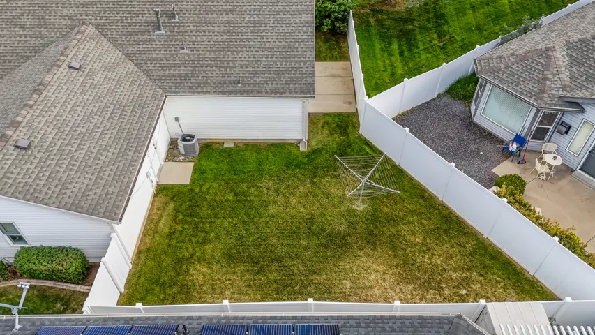 Private backyard with white fencing, a manicured lawn, and an exterior patio