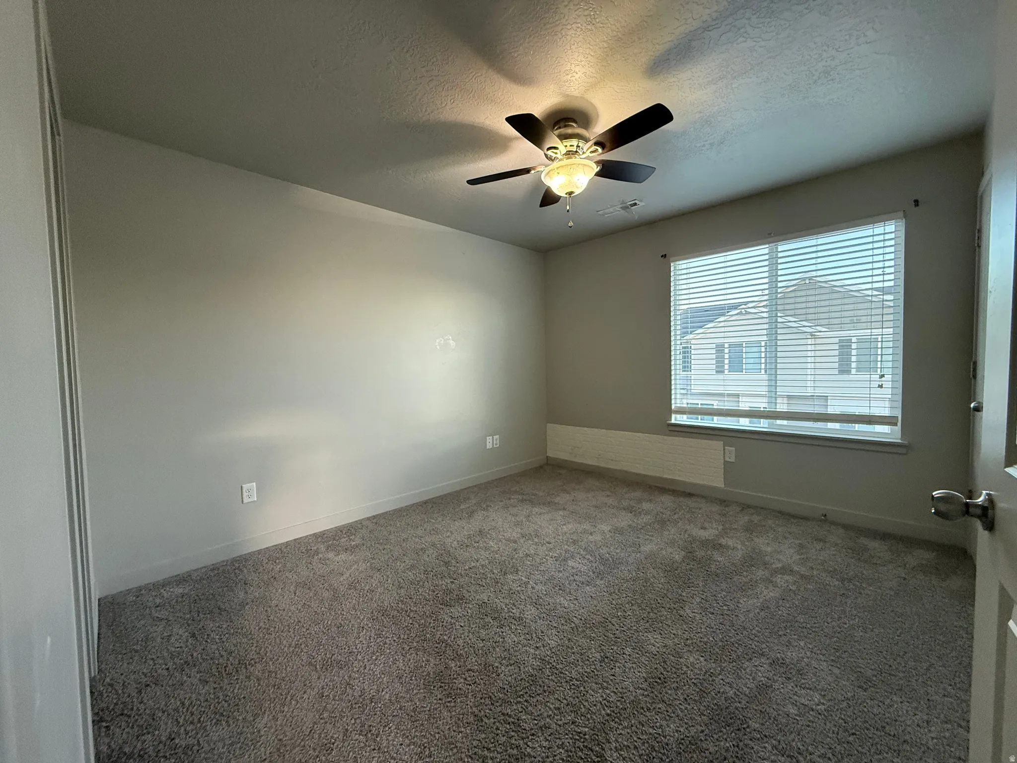 Plush carpet flooring, neutral painted walls, and a ceiling fan with integrated lighting