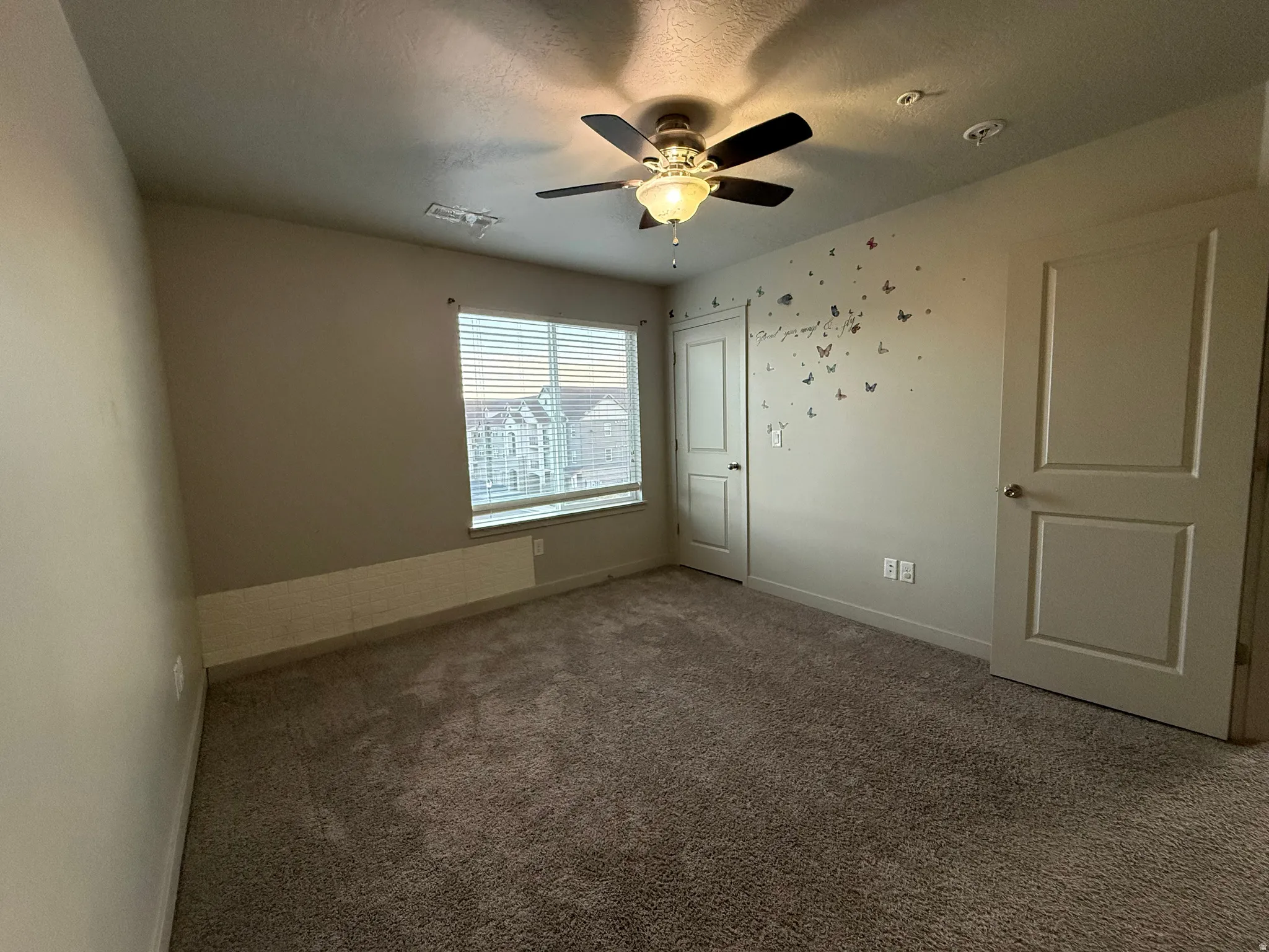 Wall-to-wall carpeting, ceiling fan with integrated lighting, and window with horizontal blinds