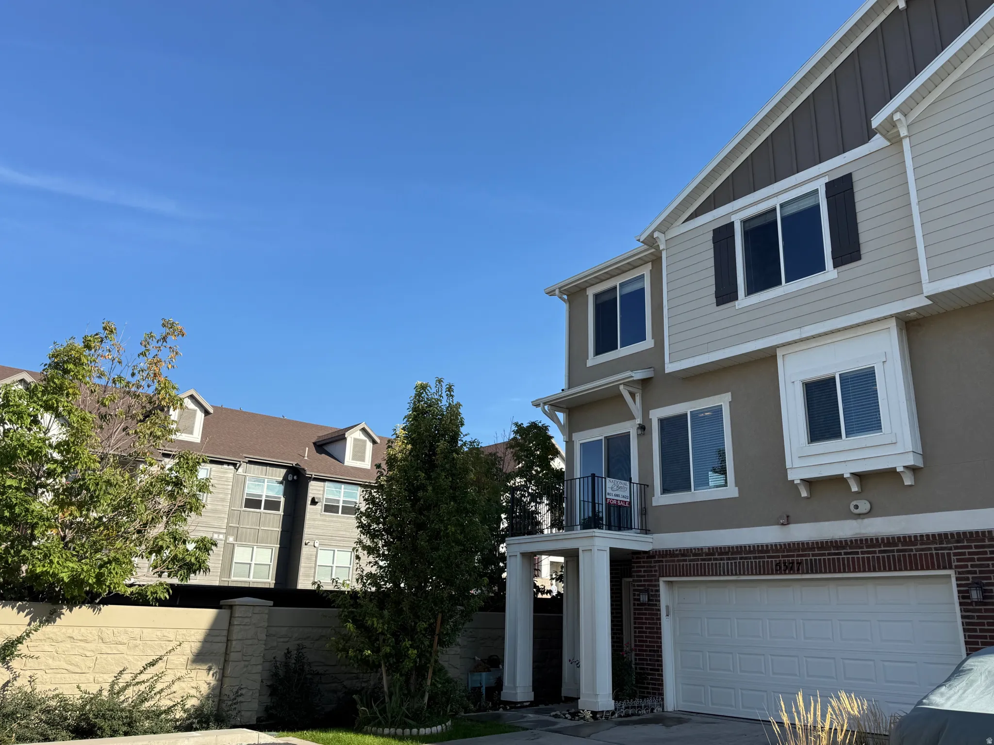 Three-story exterior featuring siding and brick accents, a two-car garage, and multiple windows with dark shutters