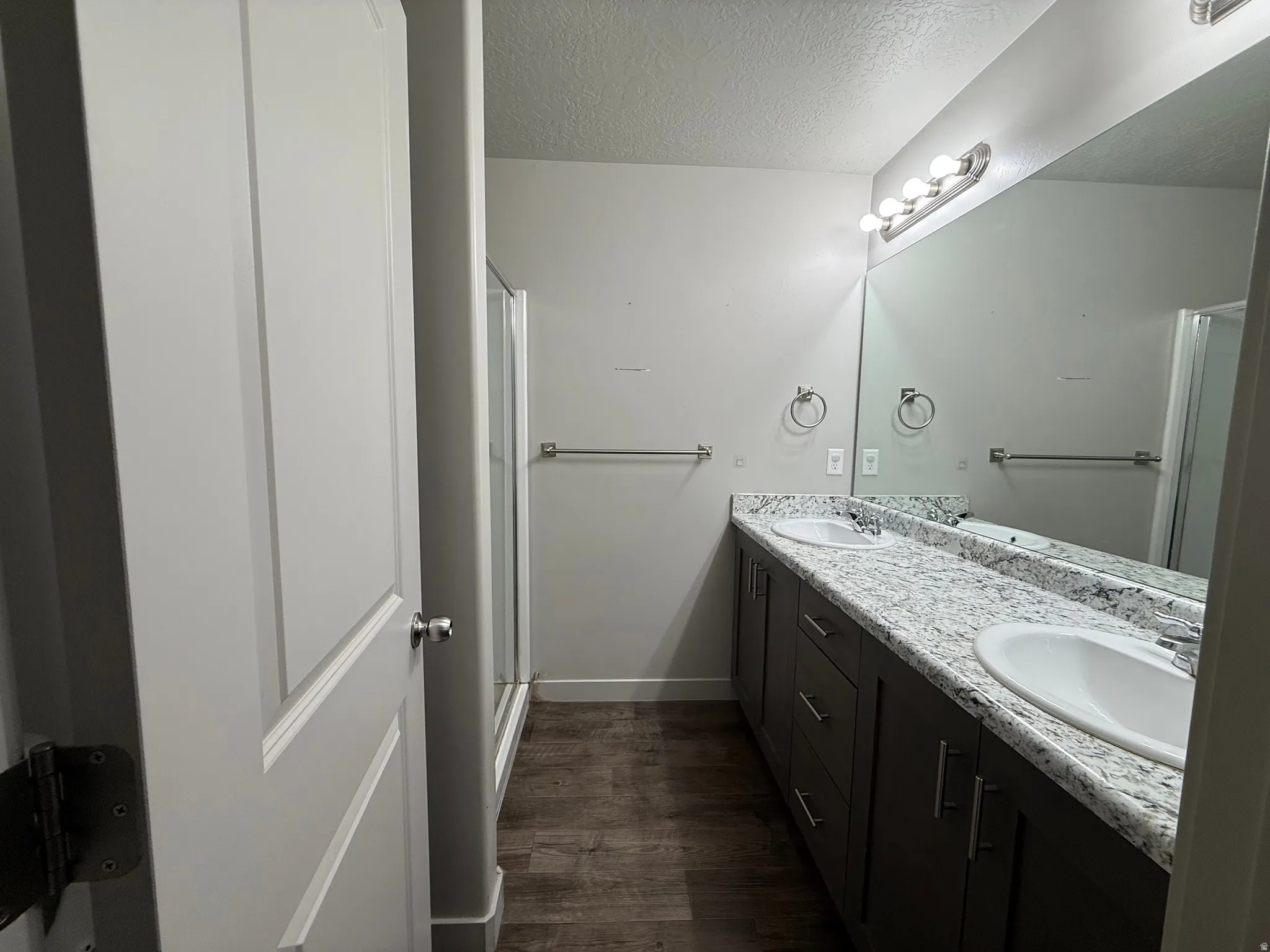 Dual vanity with white undermount sinks, speckled countertops, and dark wood-finish cabinetry
