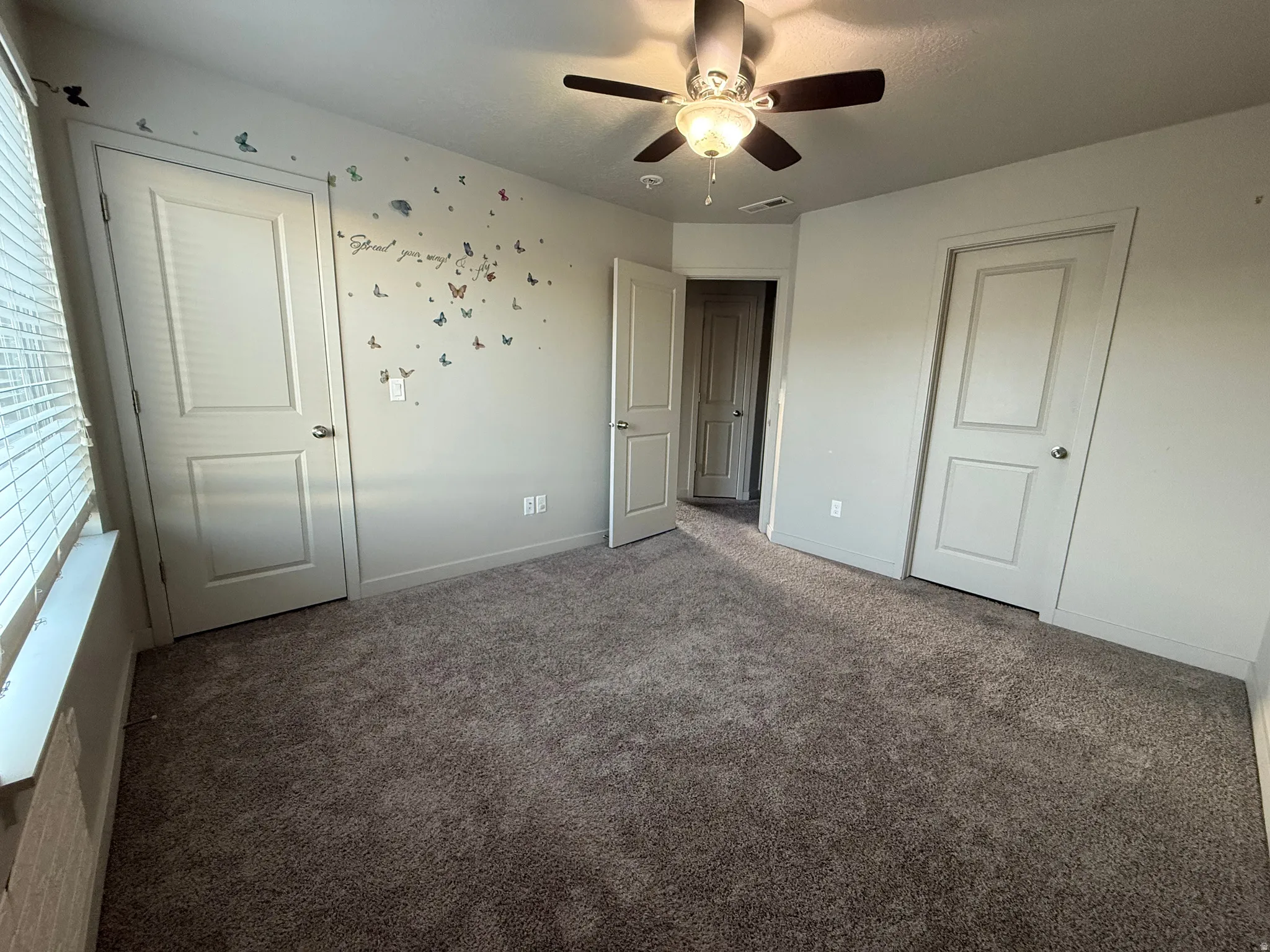 Plush carpeting, ceiling fan with integrated lighting, window with blinds, and white panel doors