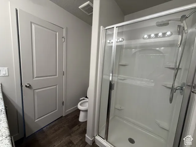 Enclosed shower with clear glass door, integrated shelving, and a shower head