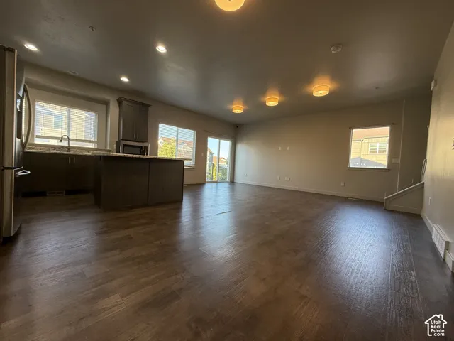 Open-concept living space featuring wood-finish flooring, recessed lighting, and a kitchen island with stone countertops