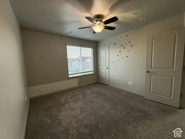 Wall-to-wall carpeting, ceiling fan with integrated lighting, and window with horizontal blinds