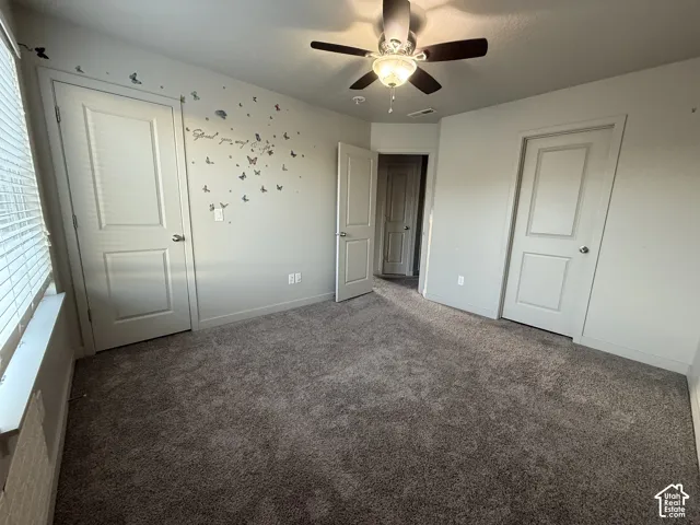 Plush carpeting, ceiling fan with integrated lighting, window with blinds, and white panel doors