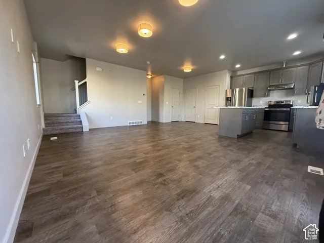 Open-concept living space featuring wood-finish flooring, recessed lighting, and a kitchen with stainless steel appliances