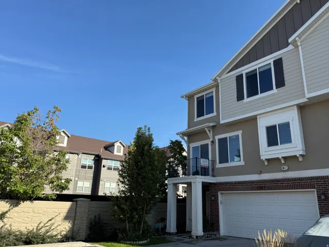 Three-story exterior featuring siding and brick accents, a two-car garage, and multiple windows with dark shutters