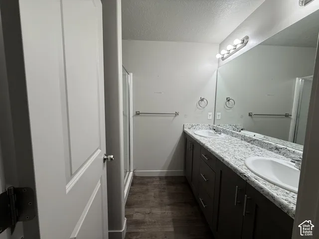 Dual vanity with white undermount sinks, speckled countertops, and dark wood-finish cabinetry