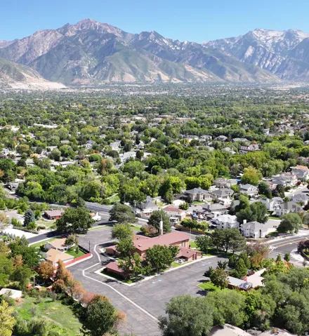Mountain backdrop with expansive urban landscape, featuring numerous residential properties and mature trees